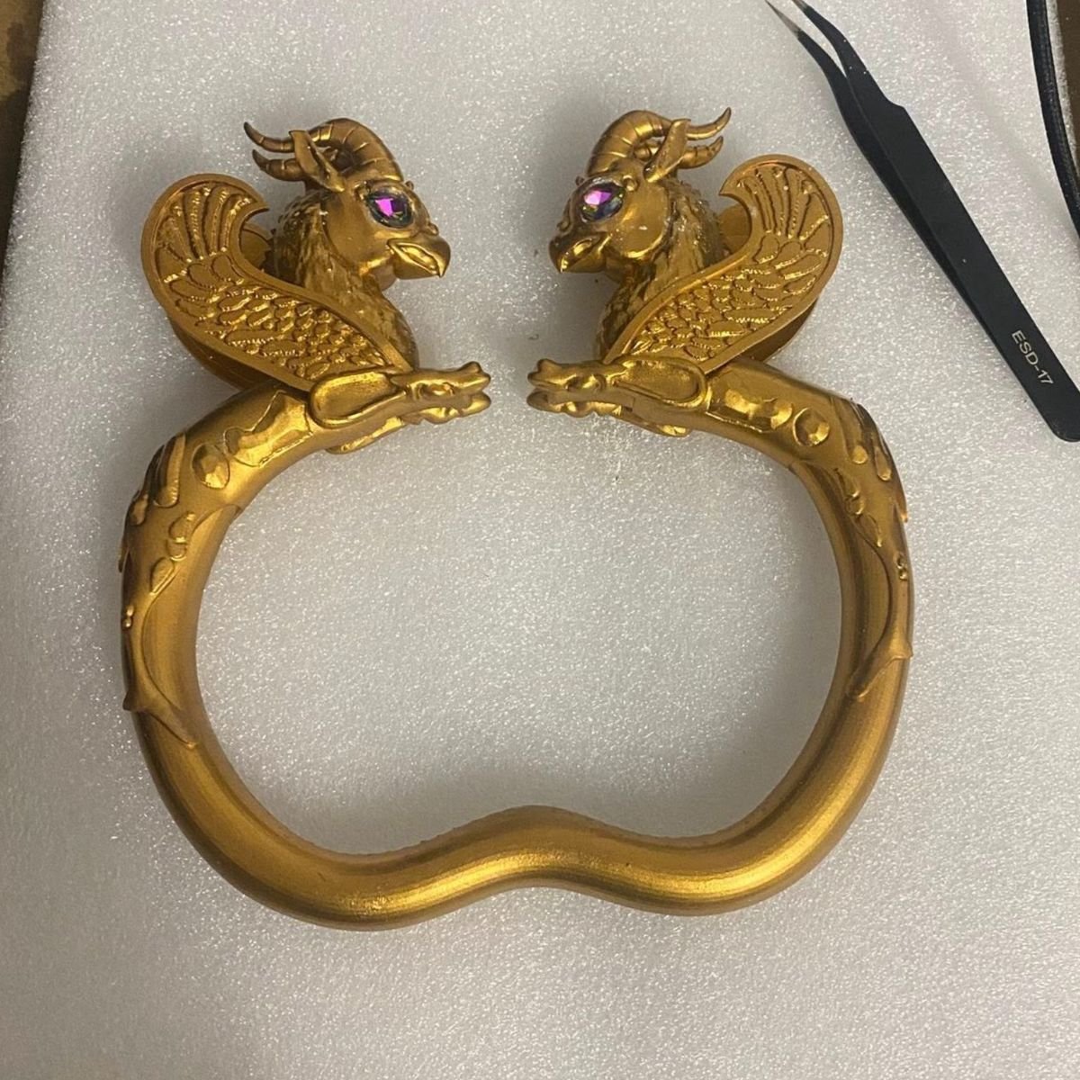 A finished gold armlet with winged ram-headed figures