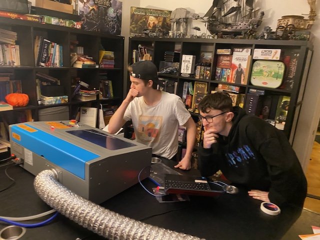 Two youth mentees learning to use a production laser cutter